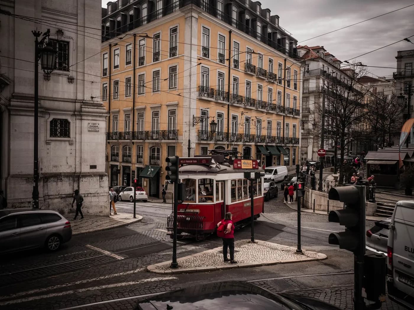 An old tram waiting at a junction on a wide Lisbon street